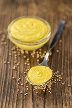 Fresh made Mustard on a vintage background (close-up shot)