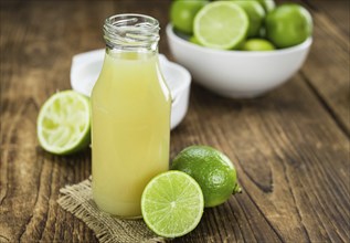 Fresh Lime Juice as high detailed close-up shot on a vintage wooden table (selective focus)