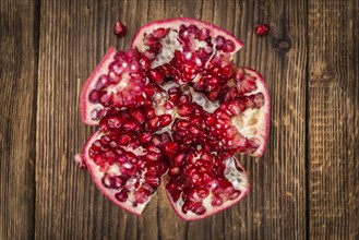 Pomegranate on an old wooden table as detailed close-up shot (selective focus)