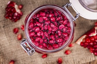 Portion of healthy preserved Pomegranate seeds on an old wooden table (selective focus, close-up