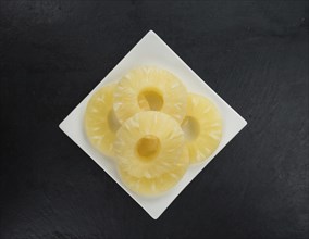 Some fresh Preserved Pineapple Rings on a vintage slate slab, selective focus, close-up shot