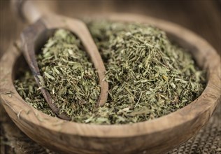 Old wooden table with dried Stevia leaves (close-up shot, selective focus)