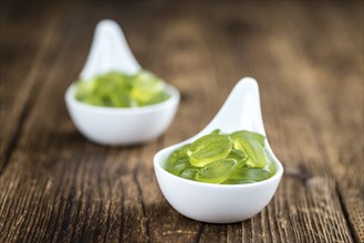 Heap of gummy candy with lime taste on wooden background (selective focus, close-up shot)