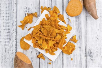 Sweet Potato Chips on an old wooden table as detailed close-up shot, selective focus