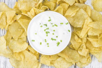 Fresh made Potato Chips with Sour Cream taste on a vintage background (close-up shot)