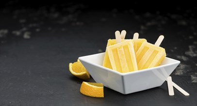 Some homemade orange popsicles on a vintage background (selective focus, close-up shot)