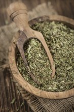 Old wooden table with dried Stevia leaves (close-up shot, selective focus)