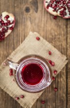 Homemade Pomegranate juice on an wooden table (selective focus) as detailed close-up shot