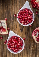 Pomegranate on an old wooden table as detailed close-up shot (selective focus)