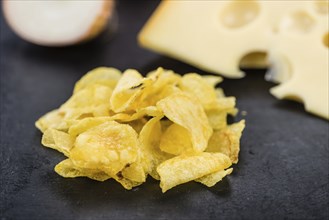 Some Potato Chips (Cheese and Onoion taste) on a slate slab (close-up shot, selective focus)