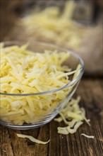 Old wooden table with grated Cheese (close-up shot)