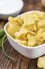 Fresh made Potato Chips with Sour Cream taste on a vintage background (close-up shot)