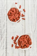 Dried Goji Berries as high detailed close-up shot on a vintage wooden table (selective focus)