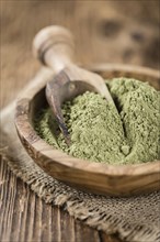 Portion of Stevia leaf powder (detailed close-up shot) on rustic wooden background