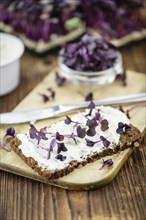 An old wooden table with healthy food (slice of bread, cream cheese and fresh cutted cress),