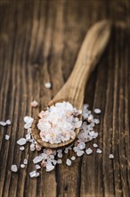 Salt (pink) on an old wooden table as detailed close-up shot (selective focus)