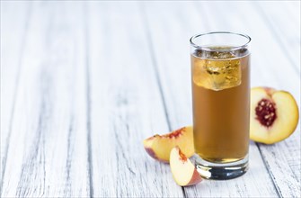 Peach ice tea (selective focus) on an old wooden table (close-up shot)