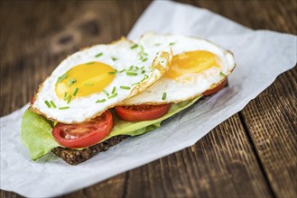 Fresh made Fried Egg Sandwich (detailed close-up shot, selective focus) on a wooden table