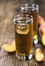 Fresh made peach ice tea (selective focus) on an old wooden table (close-up shot)