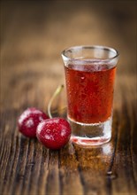 Homemade Cherry Liqueur on an wooden table as detailed close-up shot, selective focus