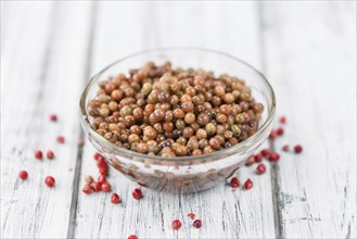 Preserved Pink Peppercorns on an old wooden table as detailed close-up shot, selective focus