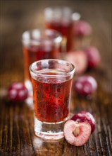 Cherry Liqueur as high detailed close-up shot on a vintage wooden table, selective focus