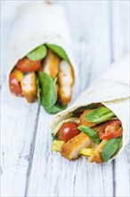 Chicken Wraps on a wooden table as detailed close-up shot (selective focus)