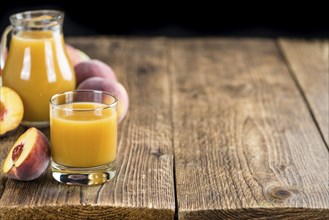 Glass of Peach juice (detailed close-up shot) on vintage wooden background