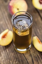 Fresh made peach ice tea (selective focus) on an old wooden table (close-up shot)