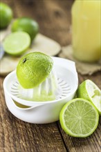 Fresh Lime Juice as high detailed close-up shot on a vintage wooden table (selective focus)