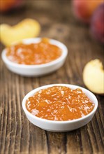 Peach Jam (selective focus) on an old wooden table (close-up shot)