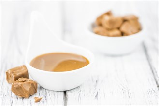 Caramel Sauce on an old wooden table as detailed close-up shot (selective focus)