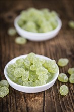 Wooden table with sour gummy candy (apple taste) as detailed close-up shot