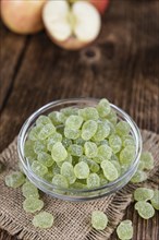 Wooden table with sour gummy candy (apple taste) as detailed close-up shot