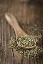 Old wooden table with dried Stevia leaves (close-up shot, selective focus)