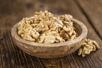 Cracked Walnuts as high detailed close-up shot on a vintage wooden table (selective focus)