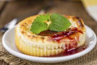 Mini Cheesecake (with Sauce) as high detailed close-up shot on a vintage wooden table (selective