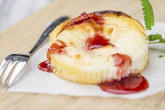 Mini Cheesecake (with Sauce) as high detailed close-up shot on a vintage wooden table (selective