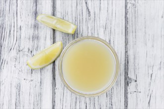 Homemade Lemon Juice on an wooden table (selective focus) as detailed close-up shot