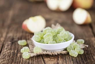 Wooden table with sour gummy candy (apple taste) as detailed close-up shot