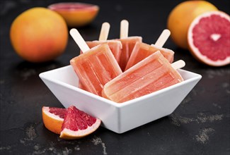 Vintage slate slab with some freshly made Grapefruit Popsicles (selective focus, close-up shot)