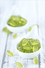 Heap of gummy candy with lime taste on wooden background (selective focus, close-up shot)