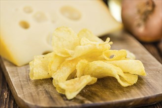 Cheese and Onion Potato Chips on an old wooden table as detailed close-up shot (selective focus)