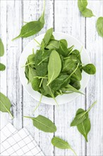 Portion of fresh Spinach on an old wooden table (close-up shot)