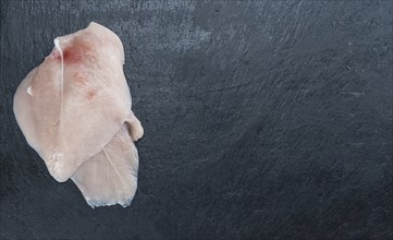 Raw Chicken Cutlet on a slate slab (detailed close-up shot)