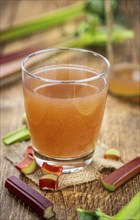 Old wooden table with fresh made Rhubarb Juice as detailed close up shot (selective focus)