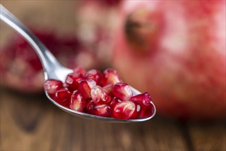 Pomegranate on an old wooden table as detailed close-up shot (selective focus)