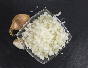 Portion of Chopped white onions as detailed close up shot on a slate slab, selective focus