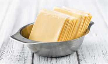 Cheese (sliced) on an old wooden table as detailed close-up shot (selective focus)