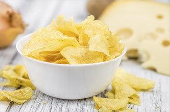 Cheese and Onion Potato Chips on a vintage background as detailed close-up shot (selective focus)